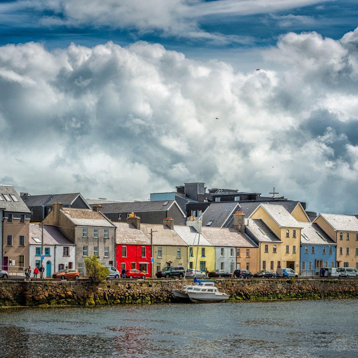 Colorful houses along the River Corrib in Galway, Ireland, with dramatic clouds overhead