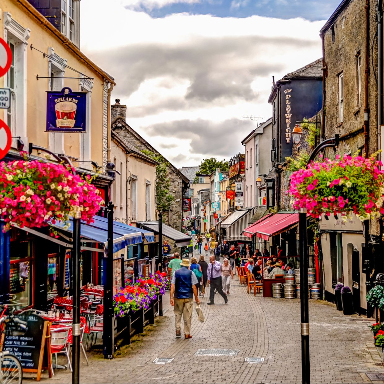 Colorful pedestrian street in Kilkenny, Ireland with cafés, shops, and hanging flower baskets